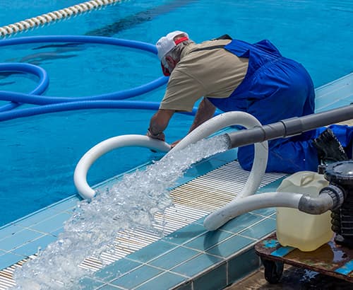 Mitarbeiter saugt Wasser aus einem Pool